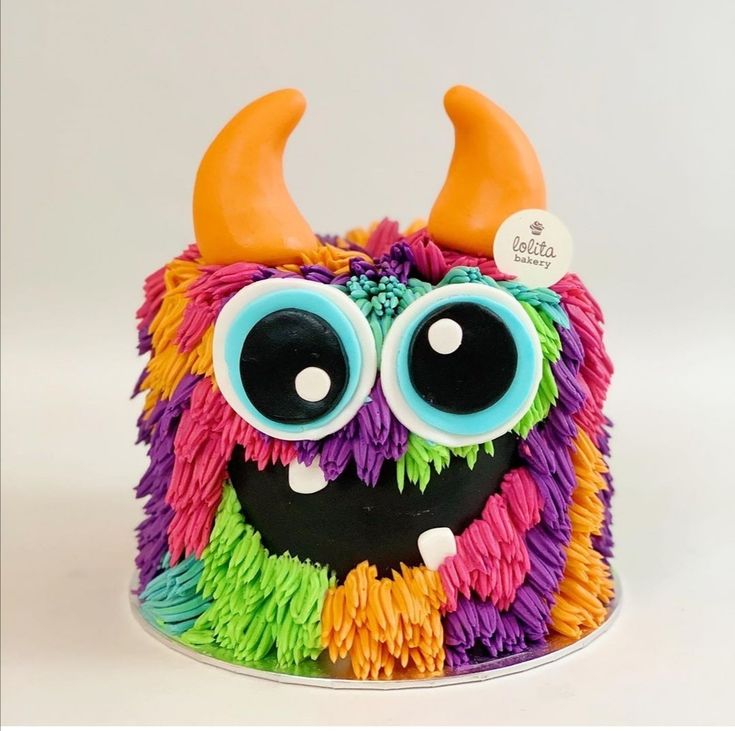 a cake decorated with multi - colored frosting and fake horns is shown in the shape of a monster