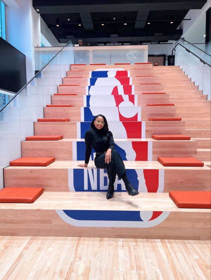 a woman is sitting on some steps in front of a sign that says i love basketball