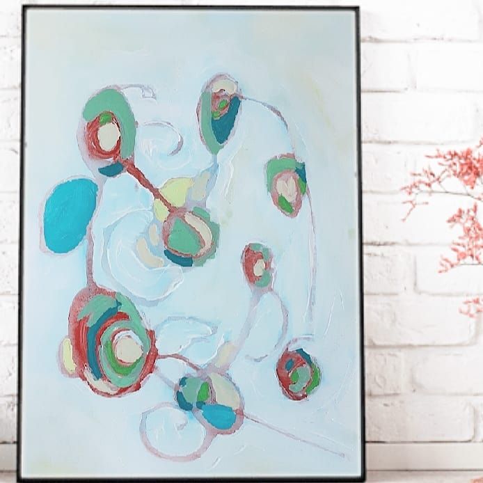 an abstract painting on a white brick wall next to a vase with red and green flowers