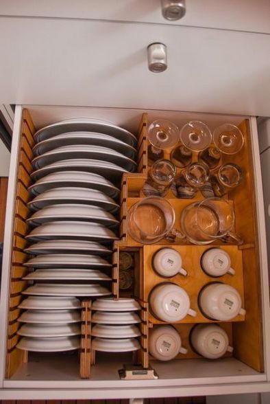 a cabinet filled with lots of dishes and plates in it's drawers, all stacked together