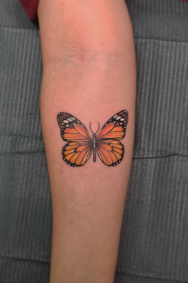 a woman's arm with a tattoo of a butterfly on the back of her leg