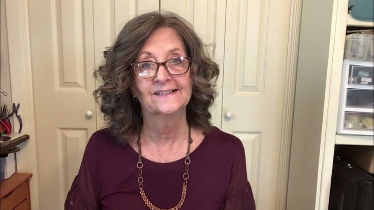 an older woman wearing glasses standing in front of a closet