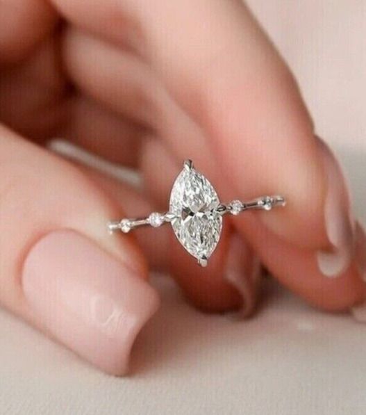 a woman's hand holding an engagement ring with a pear shaped diamond on it