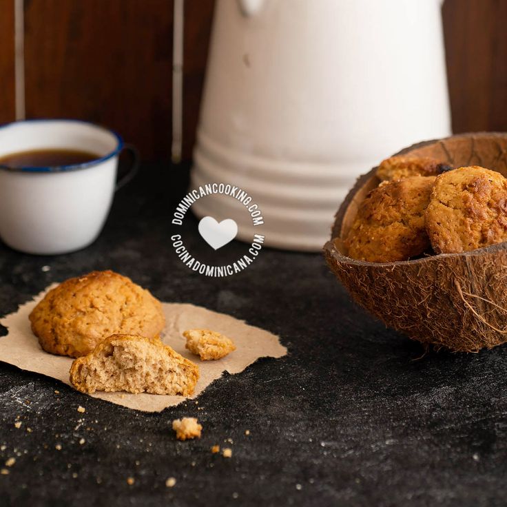 a muffin next to a cup of coffee on a black counter with a white teapot in the background