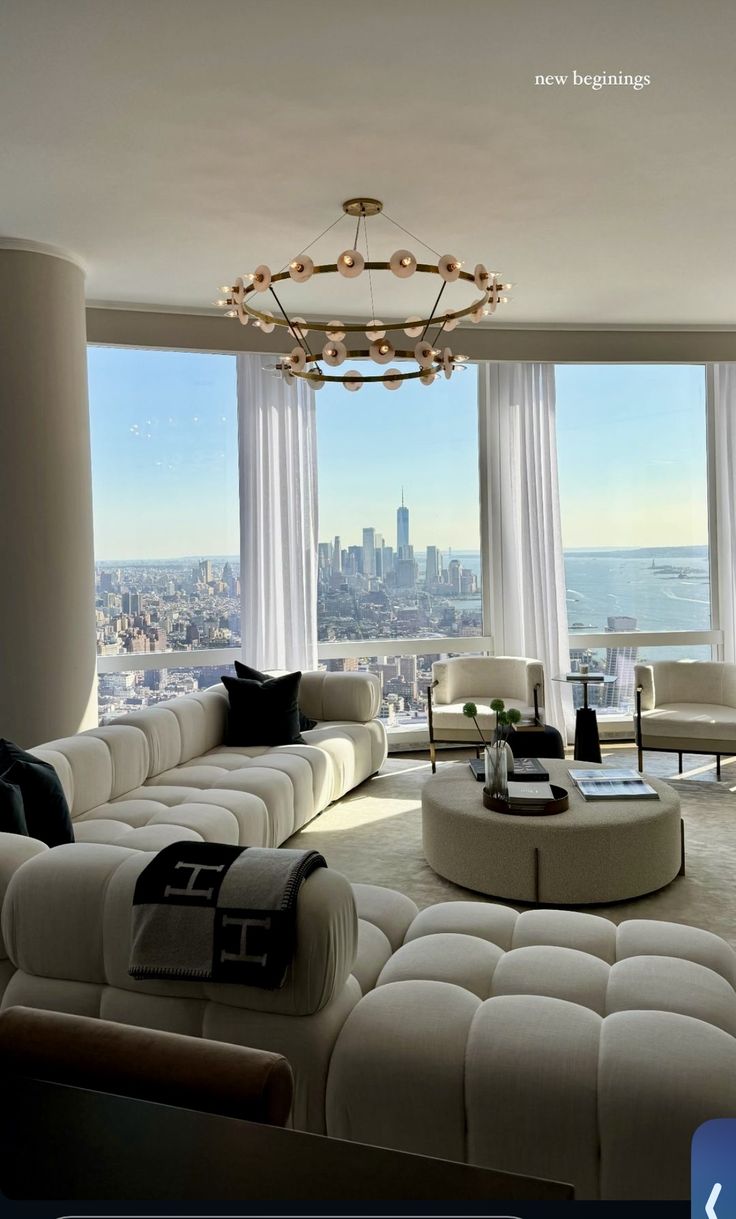 a living room filled with lots of furniture and large windows overlooking the cityscape