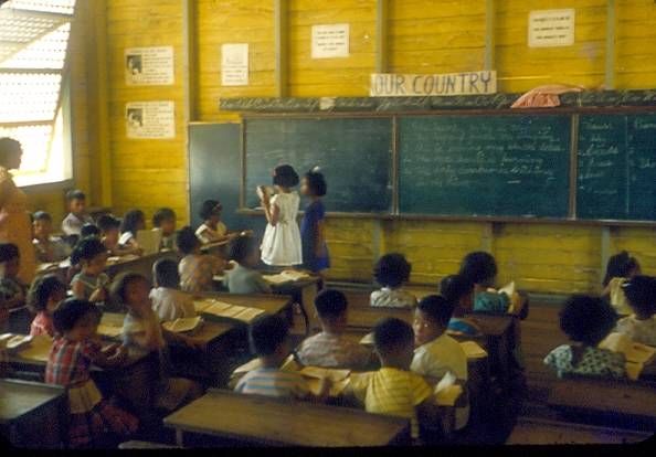 a classroom full of children sitting at desks and writing on the chalkboard in front of them