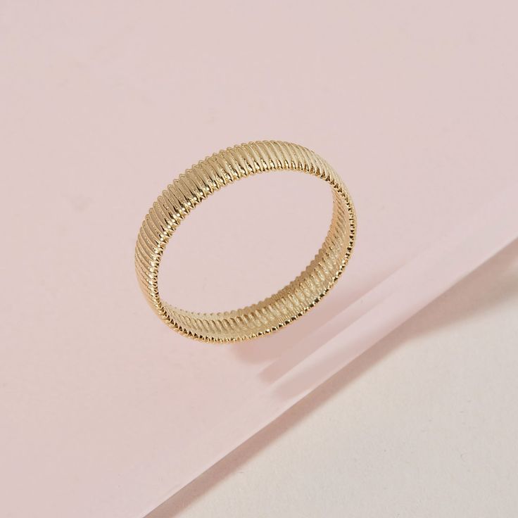 a gold ring sitting on top of a pink surface