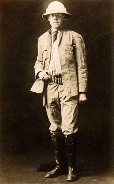 an old black and white photo of a man wearing a suit, hat, and boots