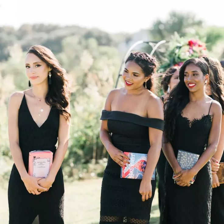 three beautiful women standing next to each other in black dresses and holding clutches on their chests