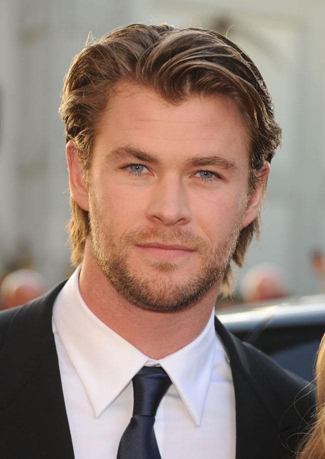 a close up of a person wearing a suit and tie with a car in the background