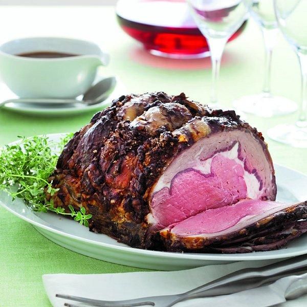 a large piece of meat sitting on top of a white plate next to silverware