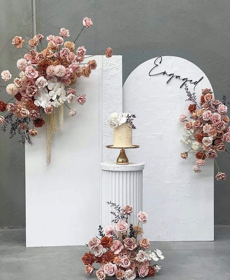 a white pedestal with flowers and a cake on it