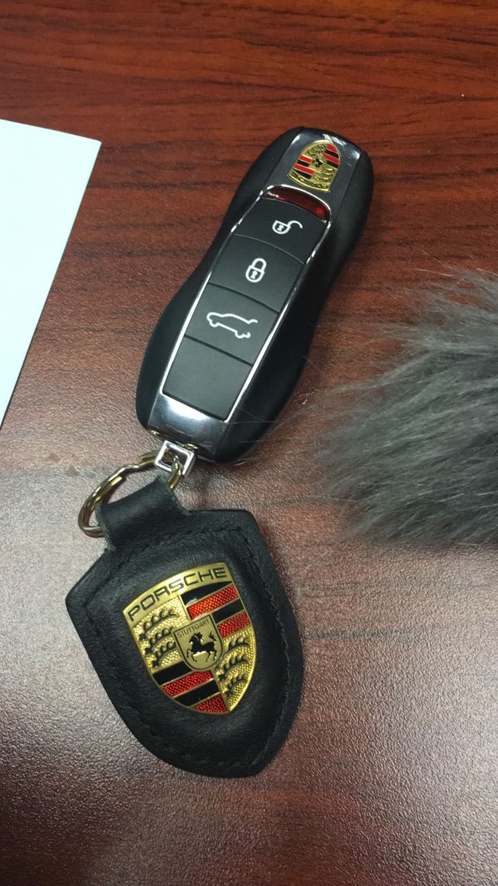 a car keychain with an emblem on it sitting next to a remote control