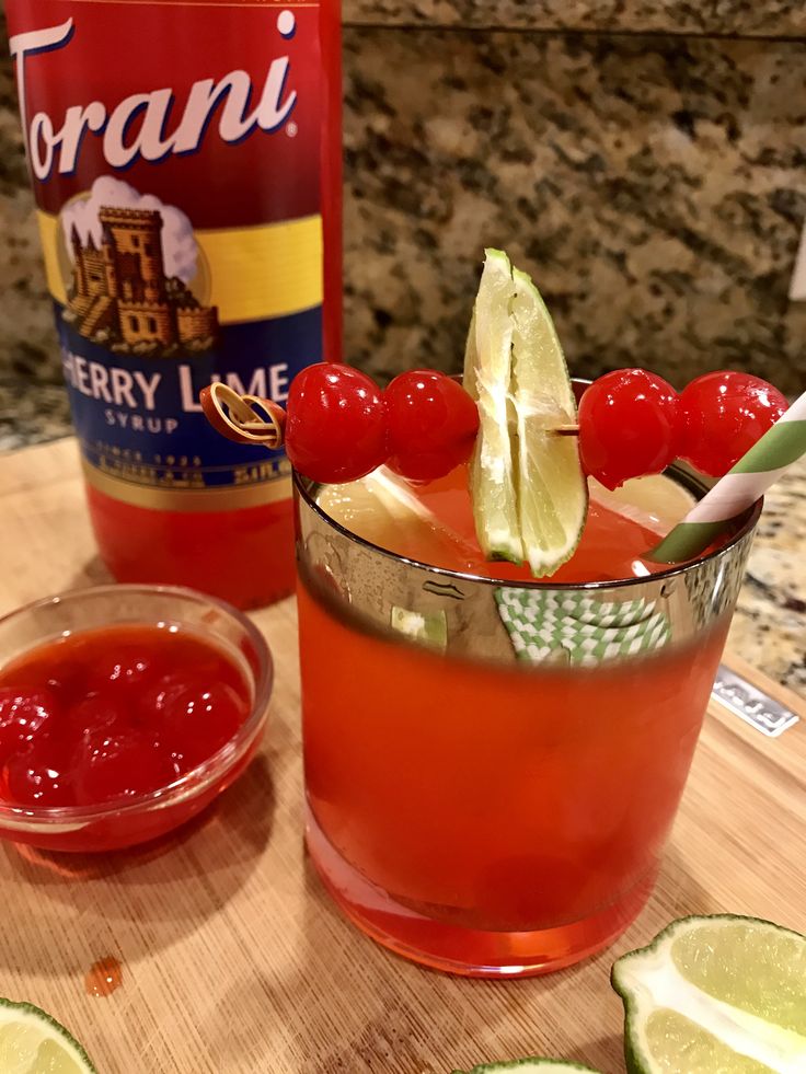 a drink with cherries and limes on the table