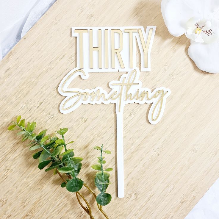 there is a cake topper that says thirty something next to some flowers on a table