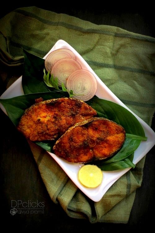 some food is on a white plate with green leaves and lemon wedges next to it