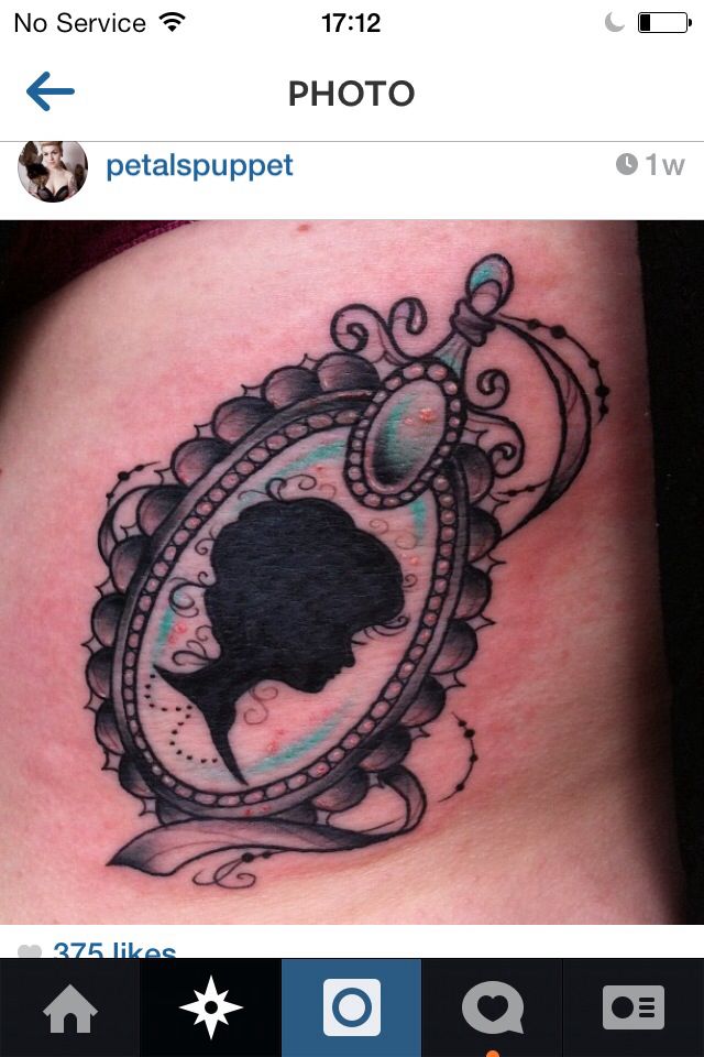 a woman's silhouette in an ornate frame tattoo on the side of her stomach