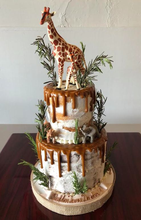 a giraffe is standing on top of a three tiered cake with icing