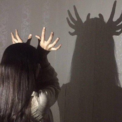 a woman standing in front of a wall with her shadow on the wall