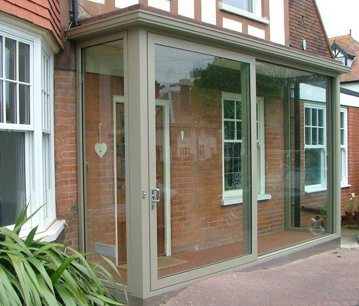 a brick building with glass doors and windows on the side of it in front of a house