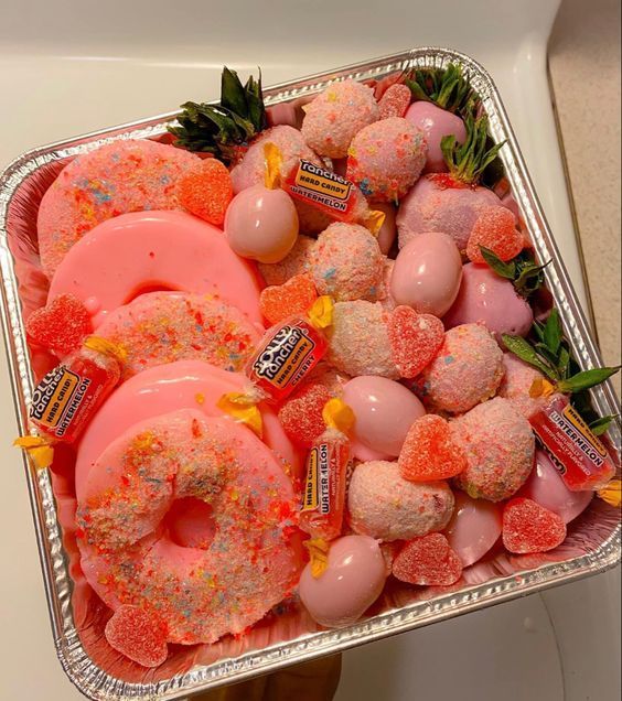 a tray filled with donuts covered in pink and orange sprinkles on top of a counter