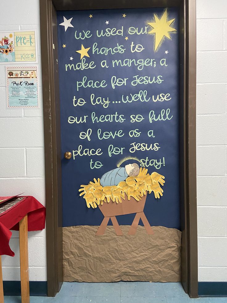 a door decorated with a nativity scene and handwritten words on it, in the shape of a manger