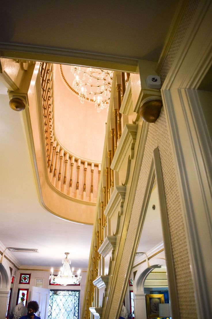 a man is walking down the stairs in front of a chandelier and window