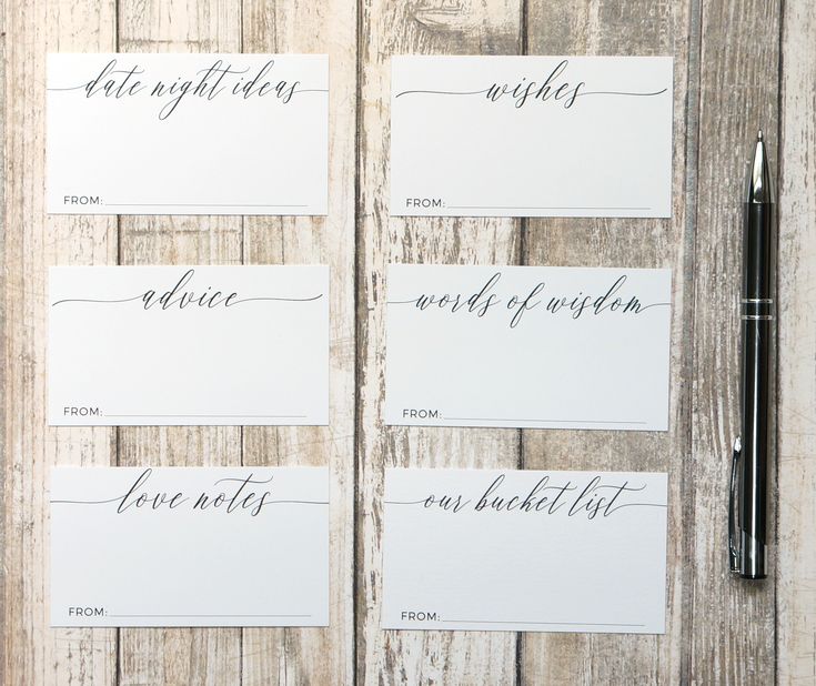 four cards with calligraphy on them sitting next to a pen and paper clipping