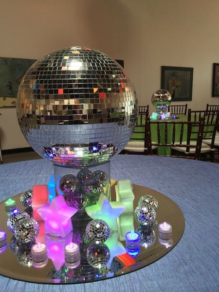 a disco ball sitting on top of a table covered in candles and confetti