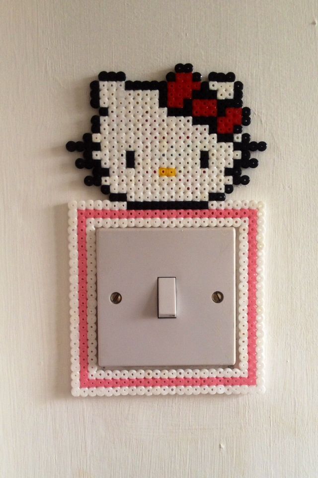 the hello kitty light switch cover is made out of plastic beads and has a pink frame around it