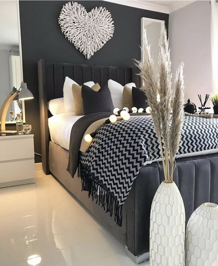 a black and white bedroom with two vases on the bed