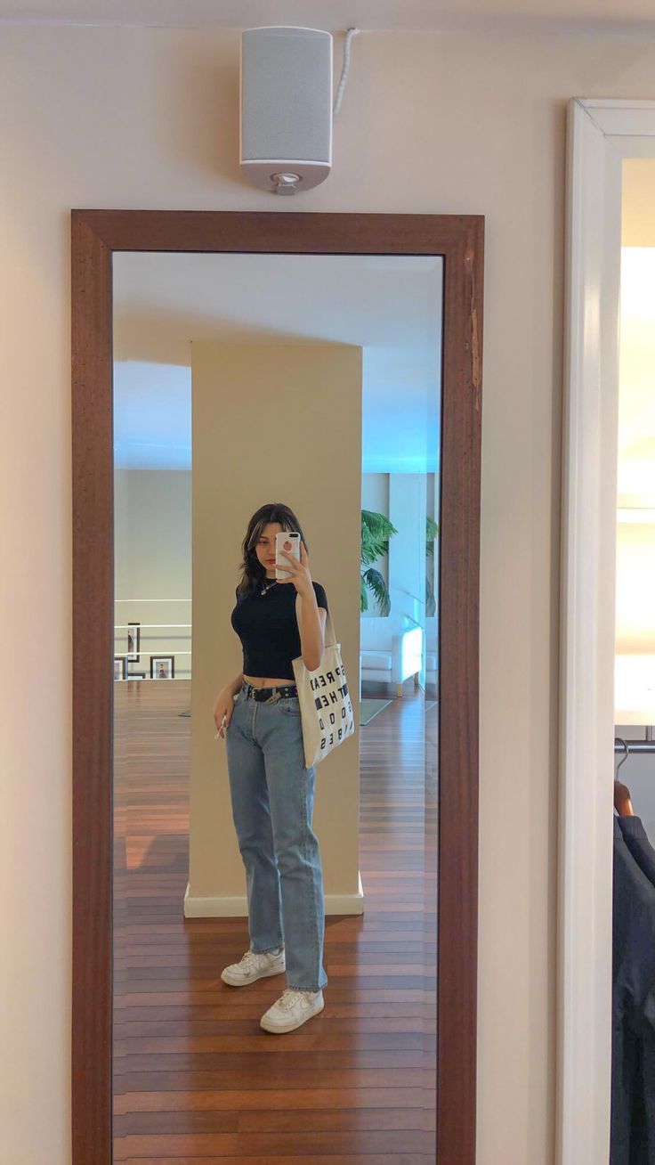 a woman taking a selfie in front of a mirror with her handbag and purse