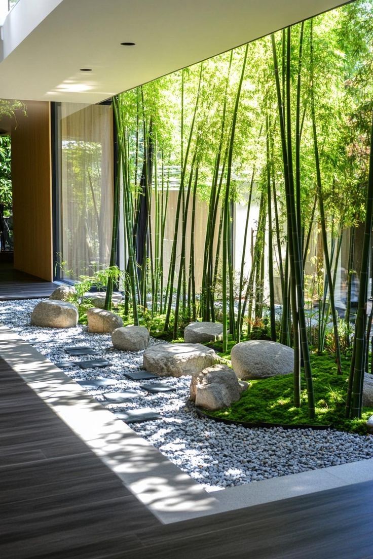 an indoor garden with rocks, grass and bamboo trees on the side of the building