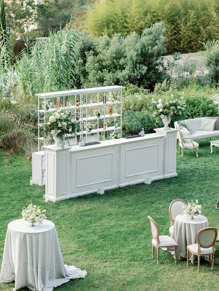 an outdoor garden with tables, chairs and flowers on the table are arranged in rows