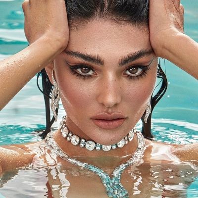 a woman in the water with her hands on her head and wearing pearls around her neck