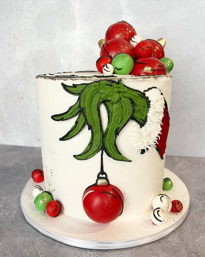 a white cake with green and red decorations on it's top, sitting on a plate