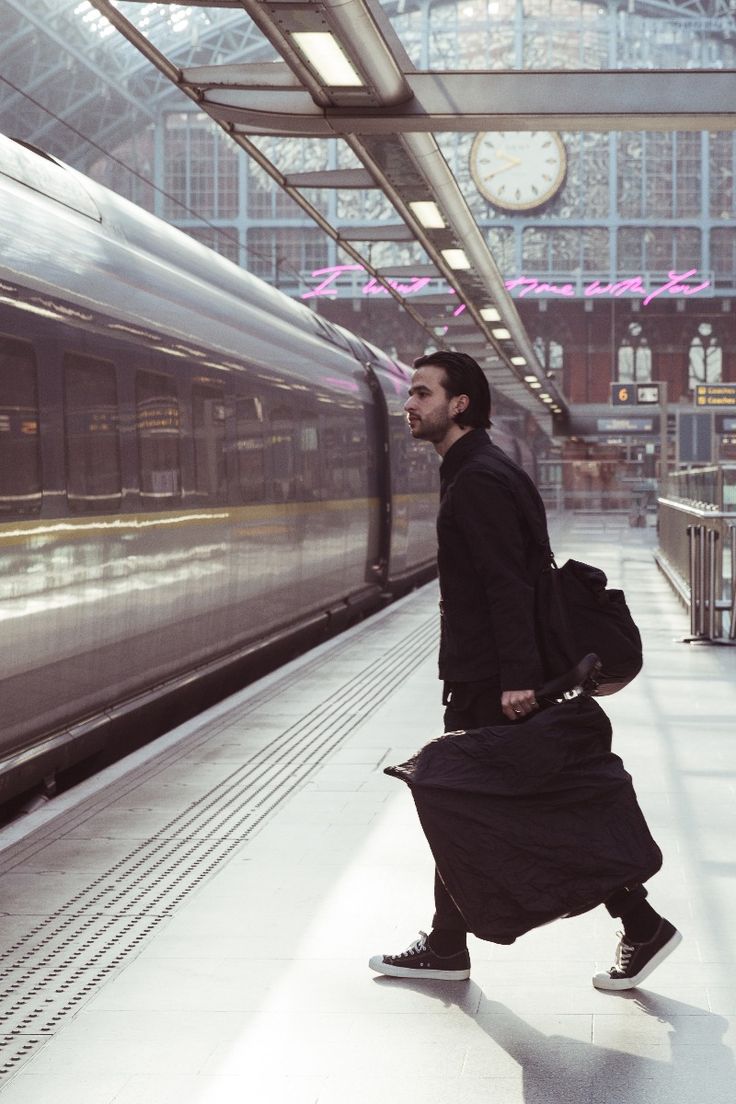 a man with a suitcase is walking in front of a train at the station,