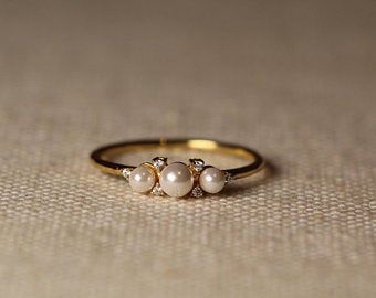 three pearls are sitting on top of a gold ring with two diamonds in the middle