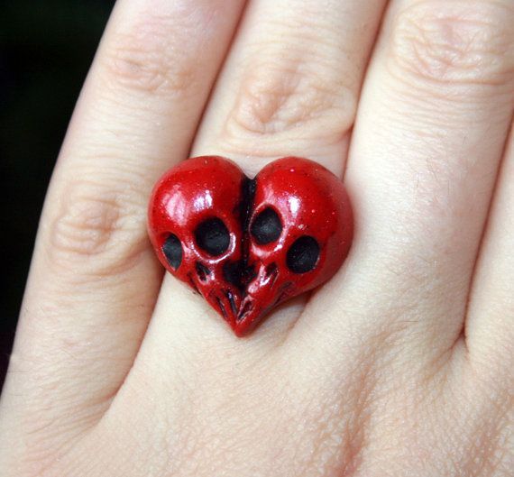 a red heart shaped ring with two skulls on it