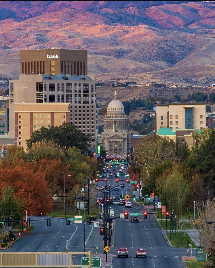 a city with mountains in the background and cars driving down the road on both sides