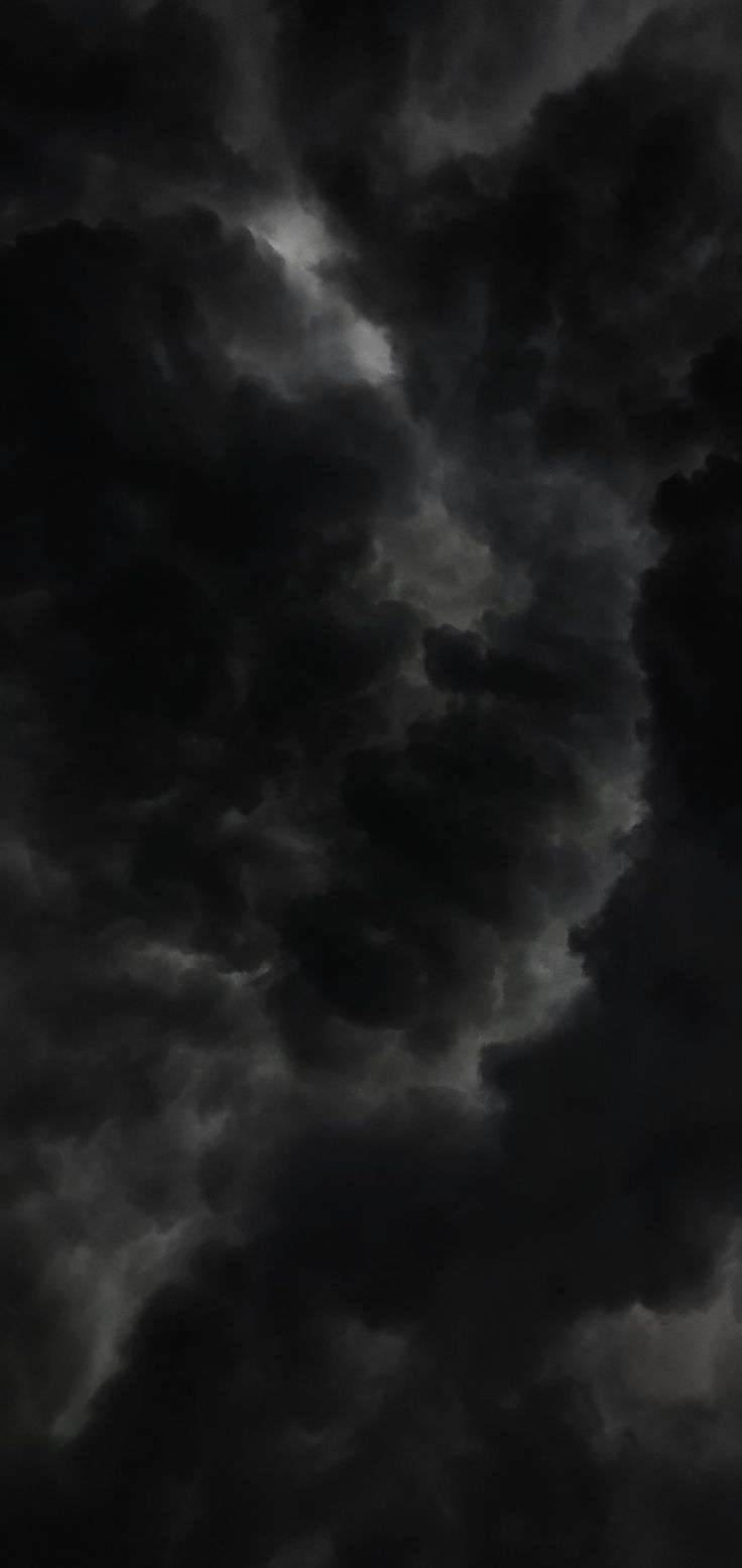 an airplane flying in the sky with dark clouds