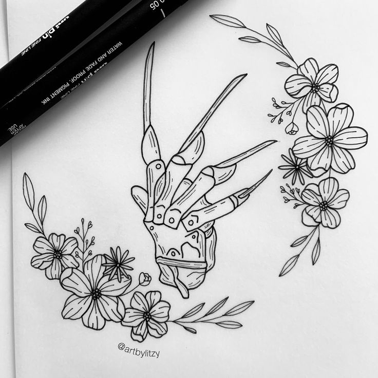 a black and white drawing of flowers with scissors in the middle, on top of a piece of paper