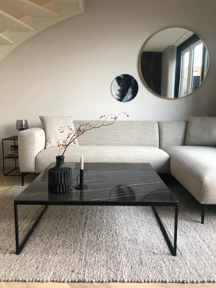 a living room with a couch, coffee table and mirror on the wall above it