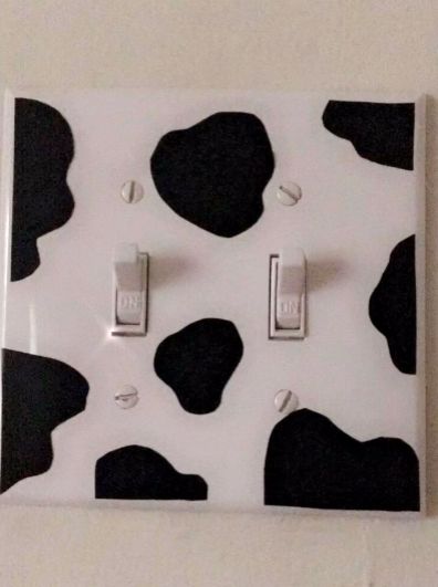 a white and black cow print light switch plate with two lights on each one side