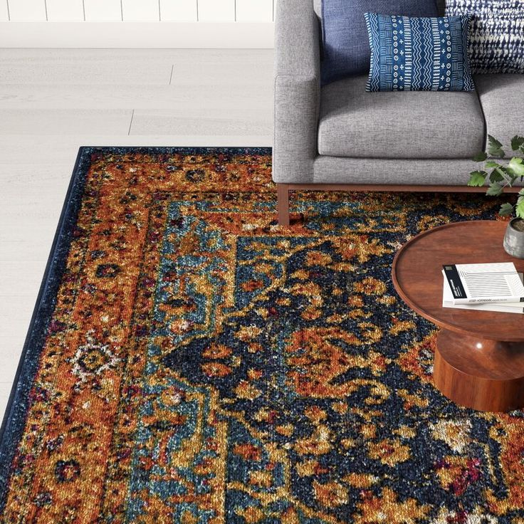 a living room area with a couch, coffee table and rug on the floor in front of it