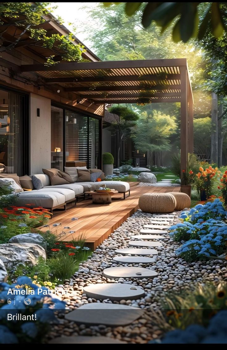 an outdoor living area is shown with flowers and rocks in the foreground, along with a stone path leading to a covered patio