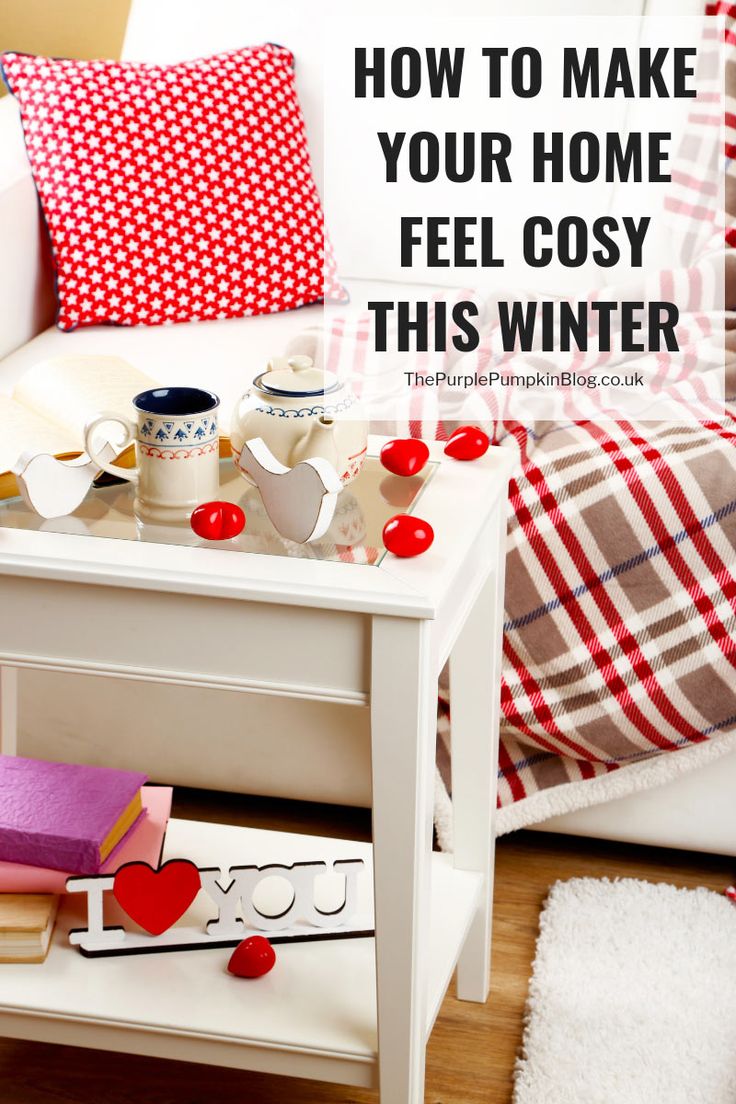 a white table with red and white pillows on it in front of a couch that has the words how to make your home feel cozy this winter