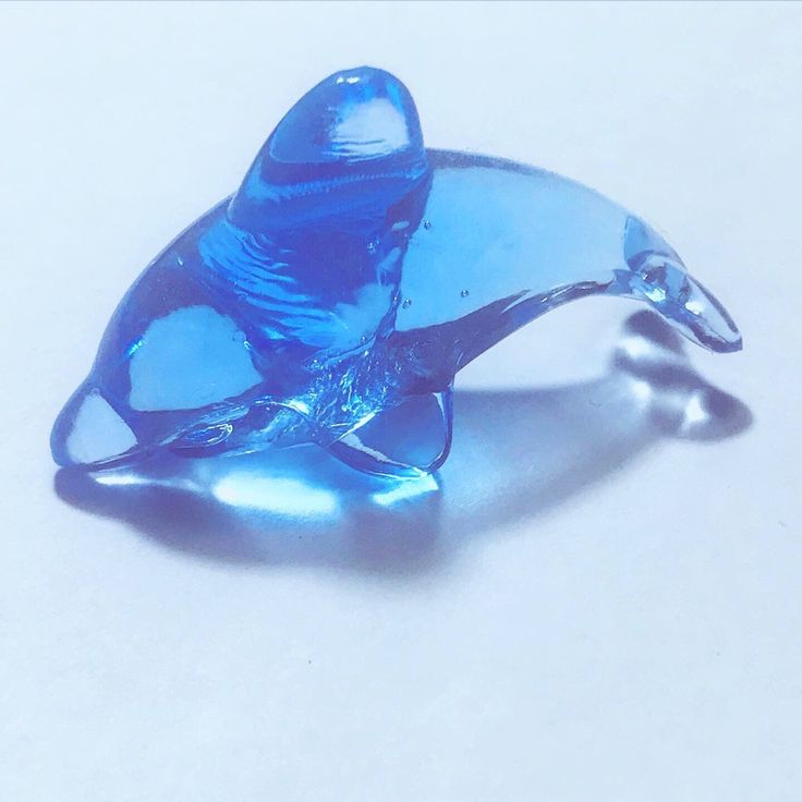 a blue glass dolphin figurine sitting on top of a table