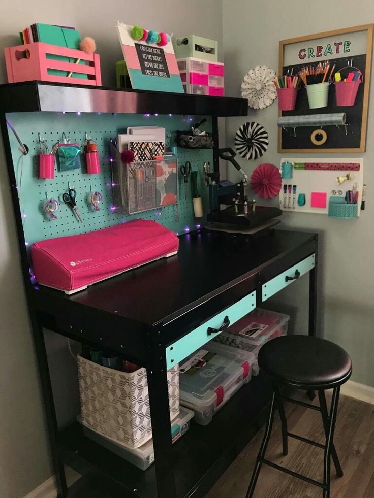 a desk with lots of crafting supplies on it and two stools next to it