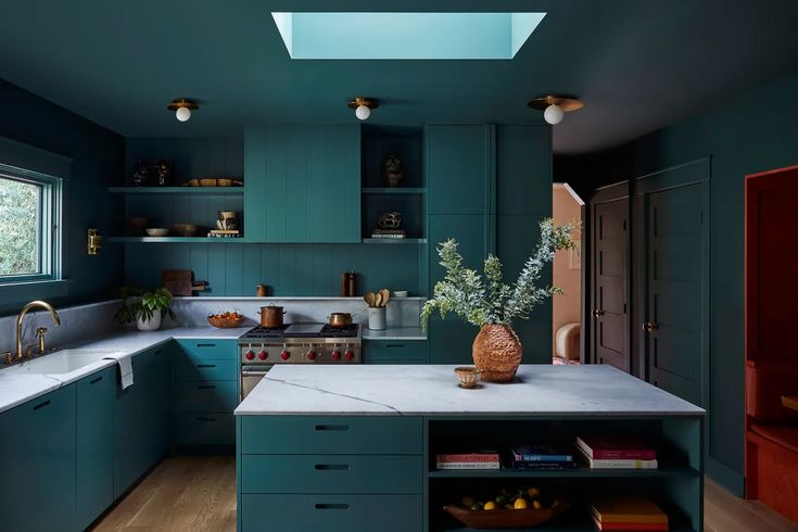 a kitchen with blue cabinets and white counter tops is pictured in this image, there are plants on the island